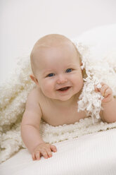 Baby-Junge (6-11 Monate) auf dem Bett liegend, lächelnd, Porträt - SMOF00400