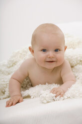 Baby boy (6-11 months) lying on bed, smiling, portrait - SMOF00394