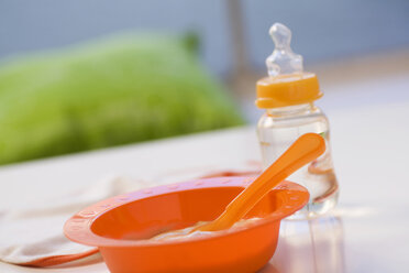 Baby food in bowl with baby bottle in background - SMOF00388