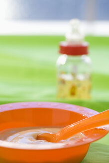 Baby food in bowl with baby bottle in background - SMOF00387