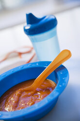 Baby food in bowl with baby bottle in background - SMOF00380