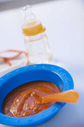 Baby food in bowl with baby bottle in background - SMOF00379