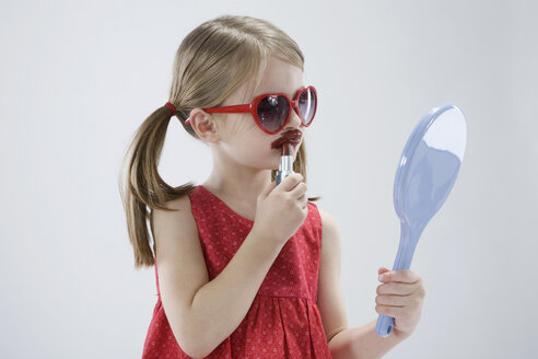 Mädchen (4-5) trägt eine Sonnenbrille und spielt mit Lippenstift - RBF00248