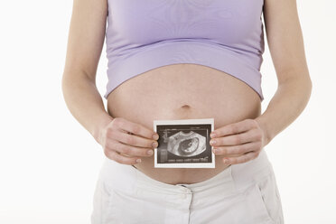 Pregnant woman holding sonogram image, midsection - RBF00212