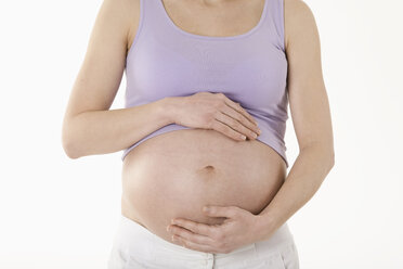 Schwangere Frau stehend mit Händen auf dem Bauch, Mittelteil - RBF00207