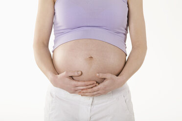 Schwangere Frau stehend mit Händen auf dem Bauch, Mittelteil - RBF00206