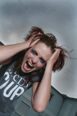Eine Frau zieht an ihren Haaren und sieht wütend aus., lizenzfreies Stockfoto