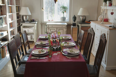 Place setting on dining table with bookshelf in background - NHF01209