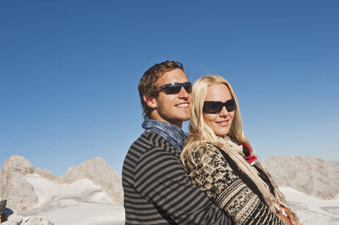 Österreich, Steiermark, Dachstein, Junges Paar mit Sonnenbrille und Umarmung, lächelnd, lizenzfreies Stockfoto
