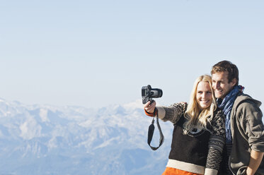 Austria, Steiermark, Dachstein, Young couple photographing on mountain, smiling - HHF03335