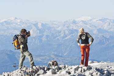 Austria, Steiermark, Dachstein, Man taking photograph of woman on mountain top - HHF03331