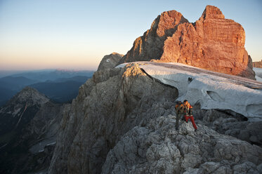 Austria, Steiermark, Dachstein, Couple hiking on mountain, standing on rock - HHF03322