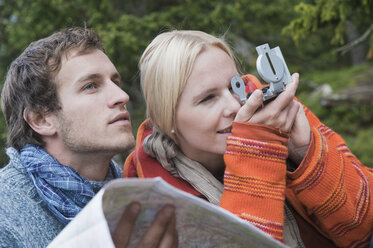 Austria, Obertauern, Man holding map, woman looking through compass - HHF03277