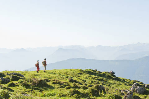 Junges Paar steht auf einem Berggipfel und betrachtet die Aussicht., lizenzfreies Stockfoto