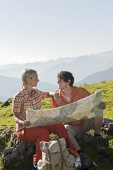 Young couple holding map, looking face to face, smiling. - HHF03230