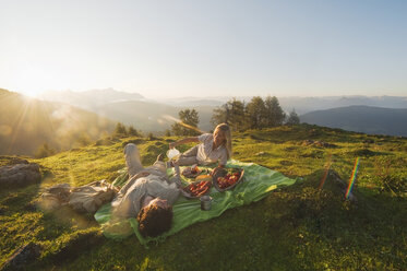 Junges Paar auf einer Decke liegend, beim Frühstück. - HHF03212