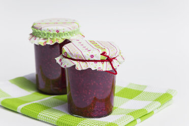 Himbeermarmelade Flasche auf Tischtuch gegen weißen HintergrundHimbeermarmelade Flasche auf Tischtuch gegen weißen Hintergrund - GWF01107