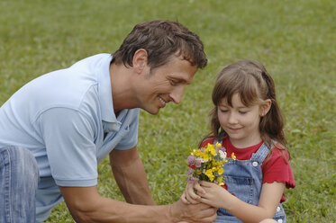 Der Vater schenkt der Tochter lächelnd Blumen. - CRF01864