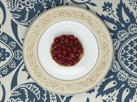 Raspberry tartlet in plate against patterned background stock photo