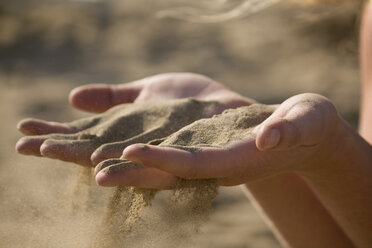 Italien, Jesolo, Jugendliches Mädchen spielt mit Sand am Strand - WVF00021