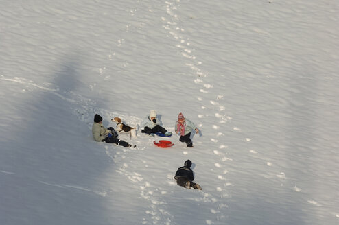 Deutschland, Mattighofen, Kinder spielen mit Hund im Schnee - SRSF00107