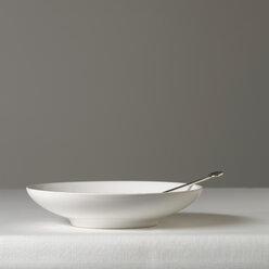 Plate with spoon against gray background - SRSF00080