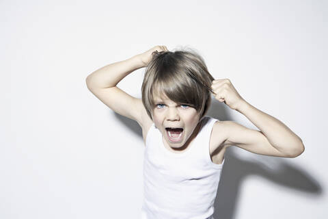 Boy (8-9) pulling hair and shouting, portrait stock photo