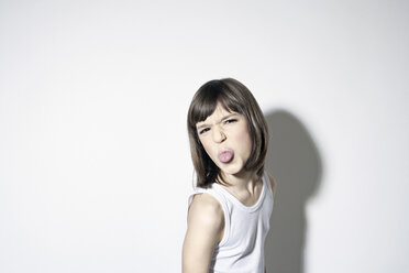 Girl (10-11) sticking out tongue against white background - PDF00007