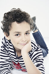 Junge (10-11) liegend mit Hand am Kinn, lächelnd, Porträt - PDF00004