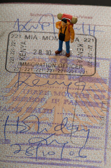 Figur eines Mannes, der auf einem Reisepass steht - AWDF00539