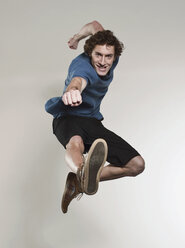 Man jumping and punching in air, smiling, portrait - FMKF00134