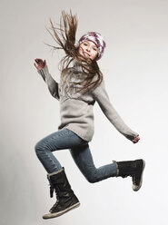 Girl (8-9) wearing woolly hat jumping, smiling, portrait - FMKF00128