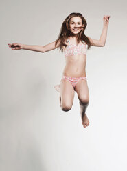 Girl (10-11) jumping and smiling, portrait - FMKF00106