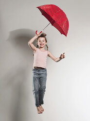 Mädchen (6-7) springend mit Regenschirm in der Hand, lächelnd, Porträt - FMKF00099