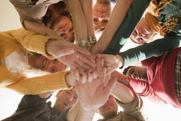 Germany, Leipzig, Group of university students putting hands together, low angle view - BABF00635