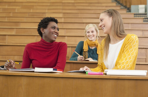 Germany, Leipzig, Students sitting and studying in auditorium, smiling - BABF00584