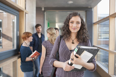 Deutschland, Leipzig, Frauen lächeln, Studenten unterhalten sich im Hintergrund - BABF00563