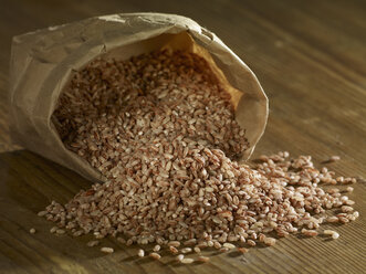 Red rice spilling on wooden surface - SRSF00196