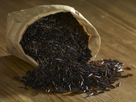 Wild rice spilling on wooden surface - SRSF00194