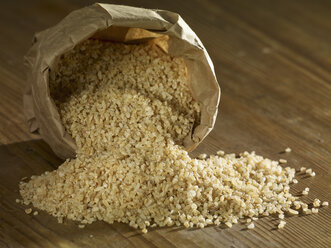 Bulgur wheat grain spilling on wooden surface - SRSF00183