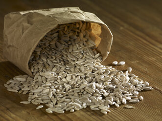 Sunflower seeds spilling on wooden surface - SRSF00171