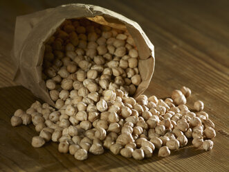 Chick-peas spilling on wooden surface - SRSF00167