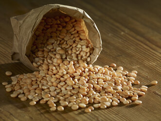 Split yellow peas spilling on wooden surface - SRSF00166