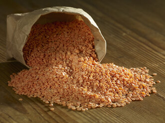 Split red lentils spilling on wooden surface - SRSF00164