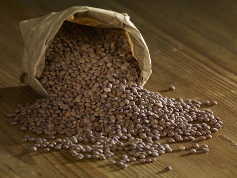 Mountain lentils spilling on wooden surface stock photo