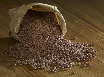 Mountain lentils spilling on wooden surface - SRSF00161