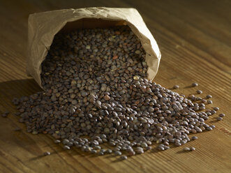 Puy lentils spilling on wooden surface - SRSF00160