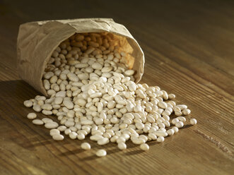 Small white beans spilled on wooden surface - SRSF00156