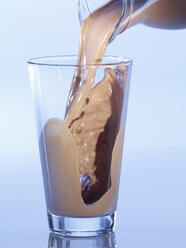 Pouring chocolate milkshake in glass, close-up - SRSF00139