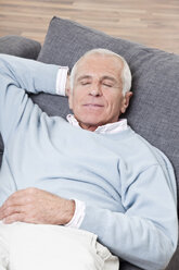 Mann mit geschlossenen Augen, auf der Couch liegend, lächelnd - CLF00918